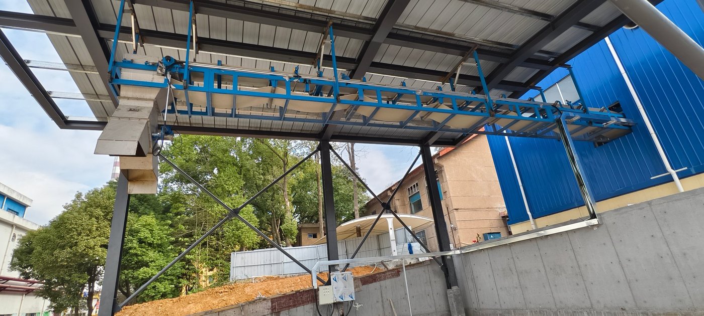 Plough discharger on a wet pulp distribution conveyor discharging into a storage bay
