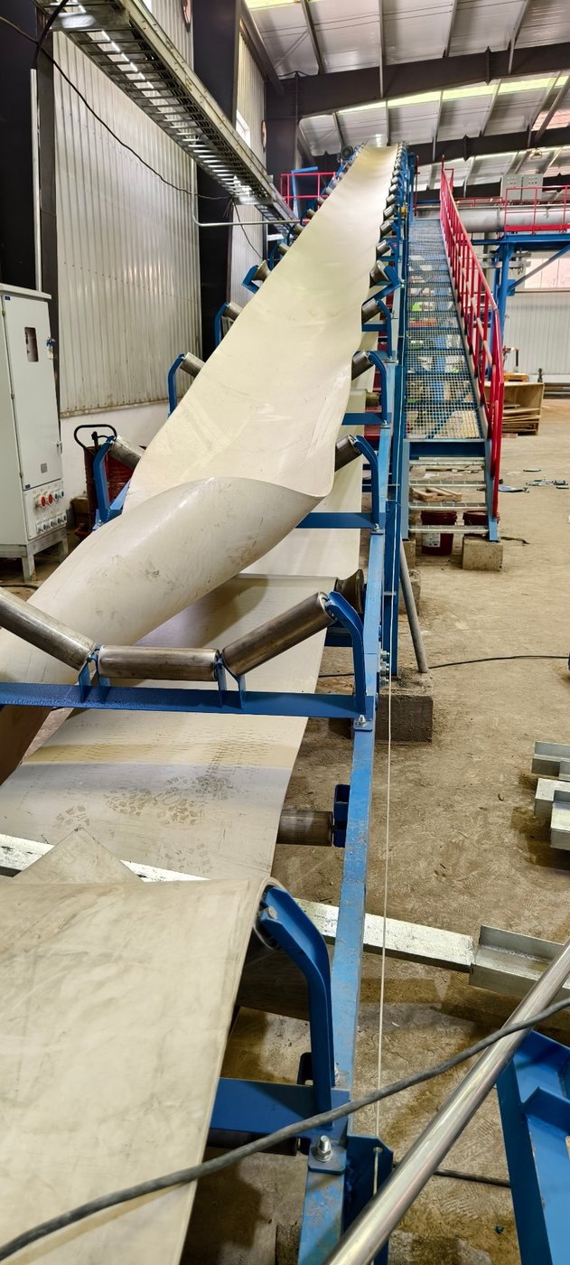 Inclined belt conveyor lifting wet pulp into the storage hall of a pulp and paper mill